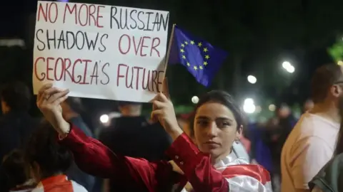 Protester holding placard that reads 'No more Russian shadows over Georgia's future'