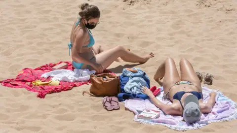 Getty Images A beachgoer wears her protective mask as she sunbathes