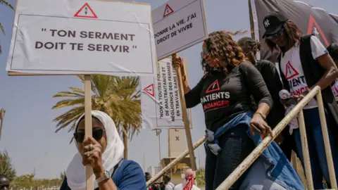 AFP Women at a protest with placards demanding justice for Astou Sokhna.