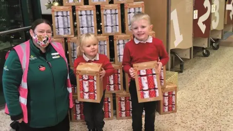 Melanie Lord Children with supermarket worker and Christmas crackers