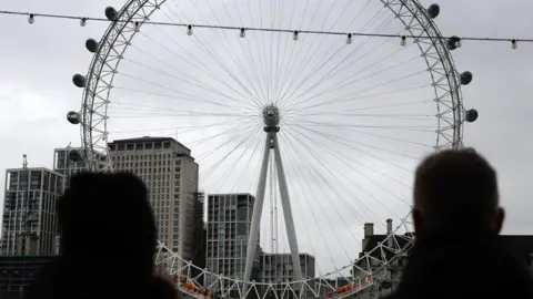 Onlookers stand by the London Eye