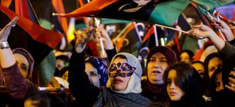 AFP Libyans wave national flags as they attend a celebration marking the seventh anniversary of the Libyan revolution which toppled late leader and strongman Moamer Kadhafi, in the capital Tripoli's Martyrs Square on February 17, 2018.