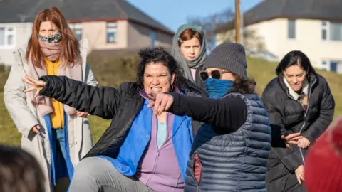Carlton Dixon Janis Pugh directing on the set of Chuck Chuck Baby surrounded by cast and crew members