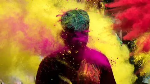 People throw coloured powder as they celebrate Holi, in Jodhpur, India, on 29 March 2021