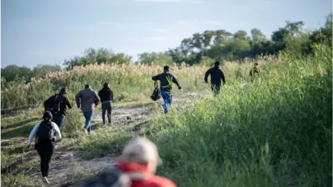 Getty Images Migrants seen looking for a crossing into the US