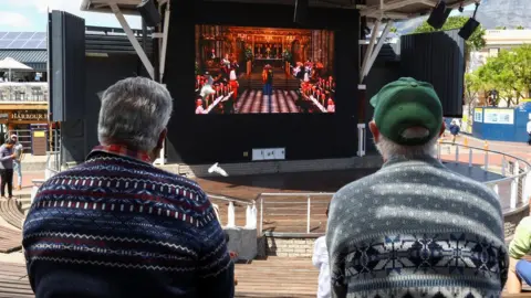 Reuters Spectators watch the service on a big screen in Cape Town