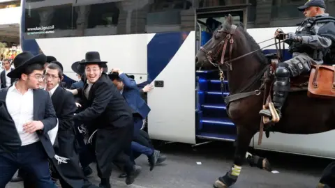 Getty Images A mounted Israeli policeman disperses a group of Ultra-Orthodox Jews during a demonstration against Israeli army conscription in the Israeli city of Bnei Brak near Tel Aviv on 1 November 2019