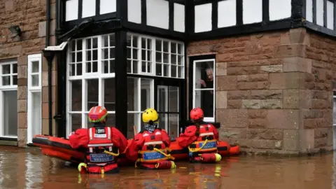 PA Wire Rescuers up to their waist in floodwater outside a house