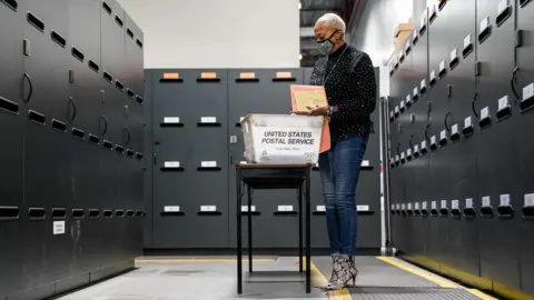 Getty Images A woman surrounded by filing cabinets looking through ballots in Georgia.