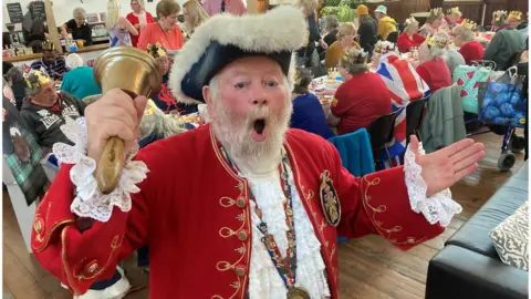 Trowbridge Town Crier, Trevor Heeks mid cry with diners seated in long tables behind him