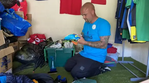 Luke Riggs cleans up a pair of donated football boots