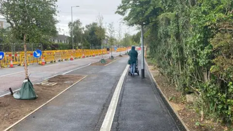 Jozef Hall/BBC Pedestrian passing lamp post on Milton Road, Cambridge