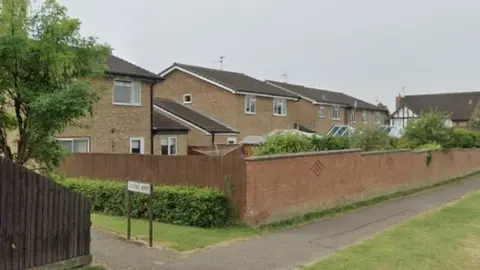 Google Modern houses behind a brick wall. A footpath to the left is signed "Lovap Way"