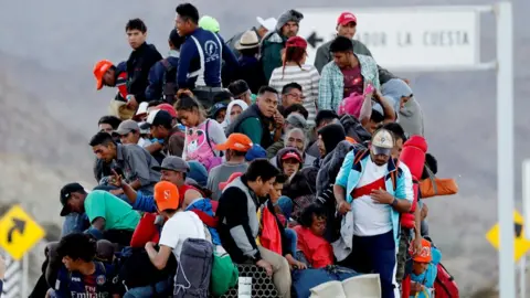 Reuters Migrants, part of a caravan of thousands travelling from Central America to the US, sit on the back of a truck en route to the Mexican border city of Tijuana, 20 November 2018