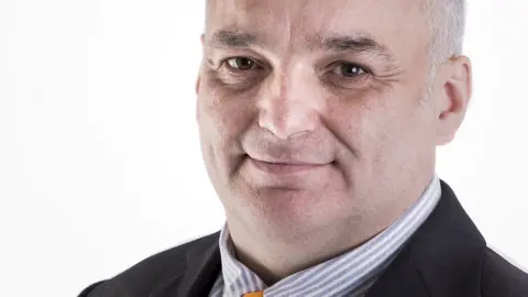 Christian Hogg Profile picture of Christian Hogg, wearing black jacket, stripy shirt, gold tie and Liberal Democrat pin badge.