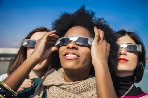 Getty Images Woman wearing solar glasses looking up at the sky