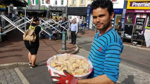 Man carrying bowl of samosas