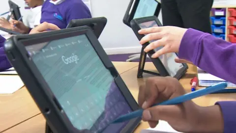 A child uses an iPad to look something up online during a lesson.