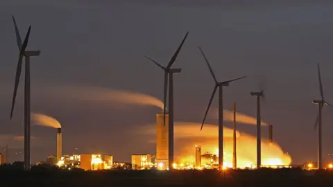 Wind turbines and manufacturing plants on the River Mersey estuary in Runcorn