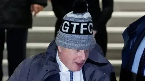 Reuters Boris John leaving the Covid inquiry in London in a hat with the initials GTFC