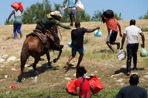 AFP A United States Border Patrol agent on horseback tries to stop a Haitian migrant from entering an encampment on the banks of the Rio Grande near the Acuna Del Rio International Bridge in Del Rio, Texas, on 19 September 2021