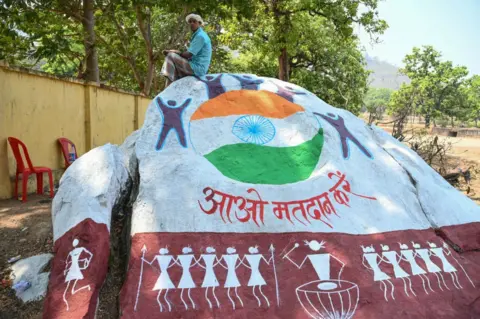 AFP A voter sits on a boulder painted with voter awareness mural,while waiting outside a polling station to cast his ballot during the first phase of voting for the India's general election, in Dugeli village of Dantewada district of Chhattisgarh state on April 19, 2024