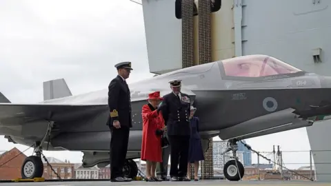Reuters Captain Angus Essenhigh and Commodore Steve Moorhouse are seen with the Queen