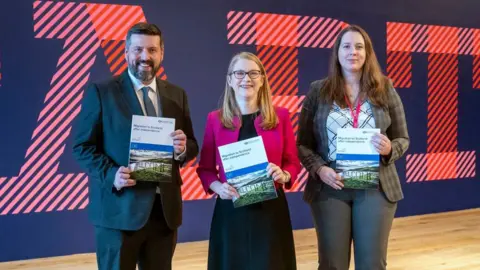 PA Media Shirley-Anne Somerville (centre) with Jamie Hepburn and Emma Rodick