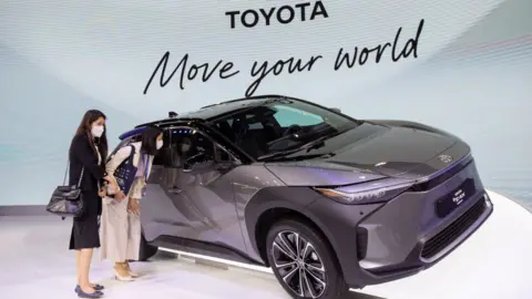 Getty Images Women looks at a Toyota bZ4X model during the 43rd Bangkok International Motor Show 2022.