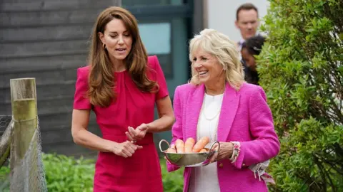 Reuters Catherine and Dr Biden walking along talking while the First Lady holds a bowl of carrots