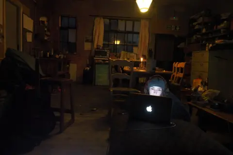 Ed Gold A woman using a laptop in a darkened room