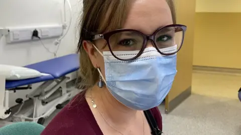 Female GP looks at camera while wearing a mask