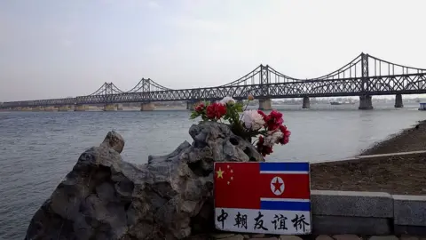 Getty Images A sign displaying the Chinese (L) and North Korean (R) flags is pictured beside the Sino-Korean Friendship Bridge which leads to the North Korean town of Sinuiju, on the banks of the Yalu River, in Dandong, northeastern Liaoning province