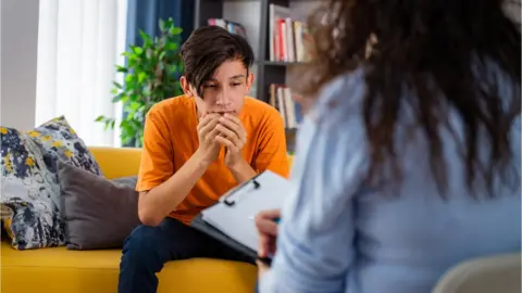 GETTY/Phynart Studio Female psychologist counseling teenage boy in office - stock photo