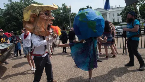 Getty Images Protesters wearing a mask of US President Donald Trump and one of the Earth pretend to fight in front of the White House during the People's Climate March in Washington, DC, on April 29, 2017