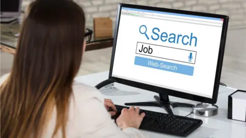 Back of woman's head doing job search on desk top computer