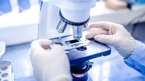 Getty Images A scientist with a microscope