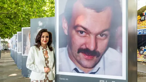 PA Media Shirley Ballas, with a picture of her brother David, at a photo installation by suicide prevention charity, Campaign Against Living Miserably