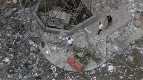 Getty Images Men walk through a debris-covered street