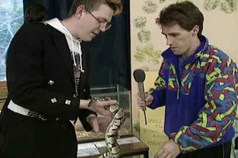 Howie Watkins hands Rob Brydon a snake live from Penscynor Wildlife Park on See you Sunday on 29 March 1992