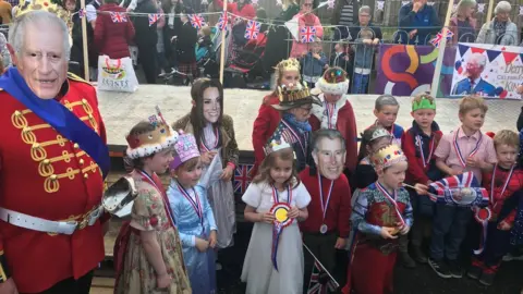 Man with King Charles mask with children dressed like royals