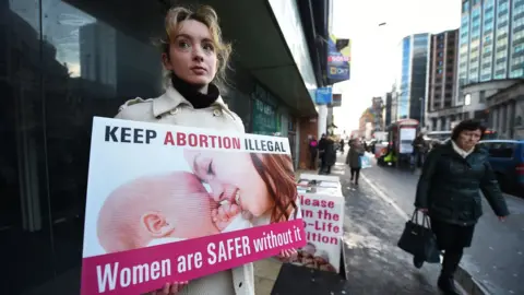 Getty Images An anti-abortion campaigner outside an abortion clinic in Belfast