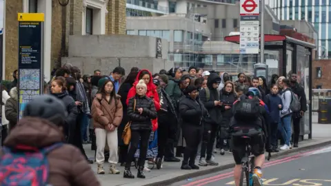 Getty Images People queue for a bus at London Bridge