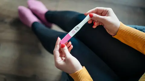 Getty Images Anonymous woman with positive pregnancy test at home