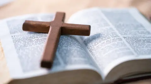 manusapon kasosod Wooden cross sits on top of open bible