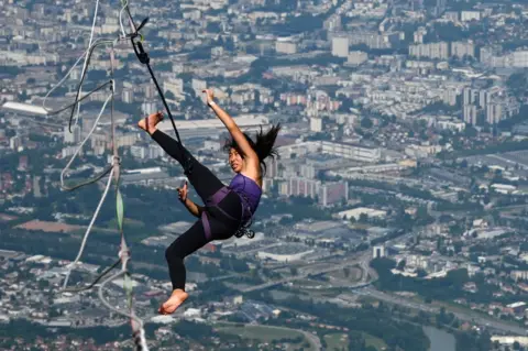 Philippe Desmazes / AFP A woman falls off a slackline