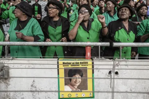 AFP Mourners sing and dance during the official funeral ceremony of late Anti-apartheid icon Winnie Madizikela-Mandela at the Orlando Stadium in Soweto on April 14, 2018 in Johannesburg, South Africa. South Africa will lay to rest anti-apartheid icon and Nelson Mandela's former wife Winnie Mandela with full state honours at a stadium funeral in Soweto on April 14. The ceremony will conclude 10 days of national mourning during which time thousands of South Africans have paid tribute to the 'Mother of the Nation' at her Soweto home and elsewhere.