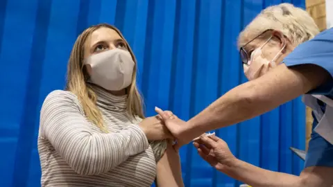 Getty Images Young woman getting a Covid vaccination from a female nurse