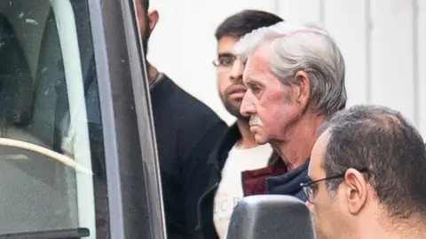 PA Media David Hunter escorted to a custody van outside court in Cyprus at a hearing on 5 December