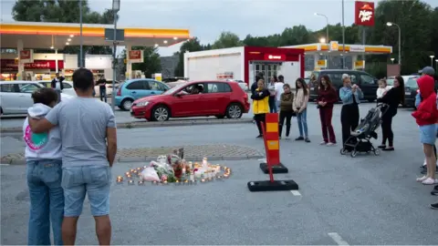 EPA People lay candles and flowers at the site where a twelve year old girl was shot near a petrol station in Botkyrka, south of Stockholm, Sweden, 03 August 2020.